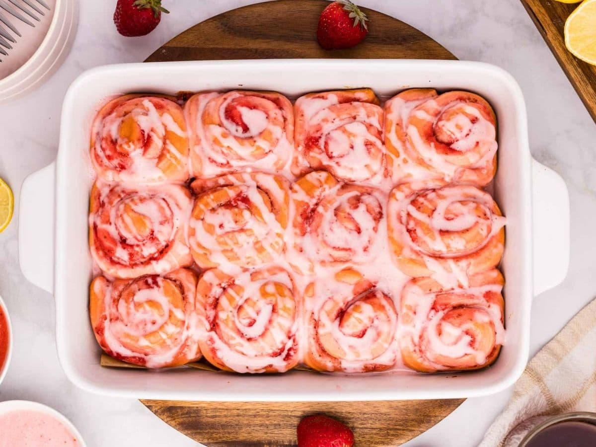 Overhead shot of finished strawberry cinnamon rolls in a baking dish.
