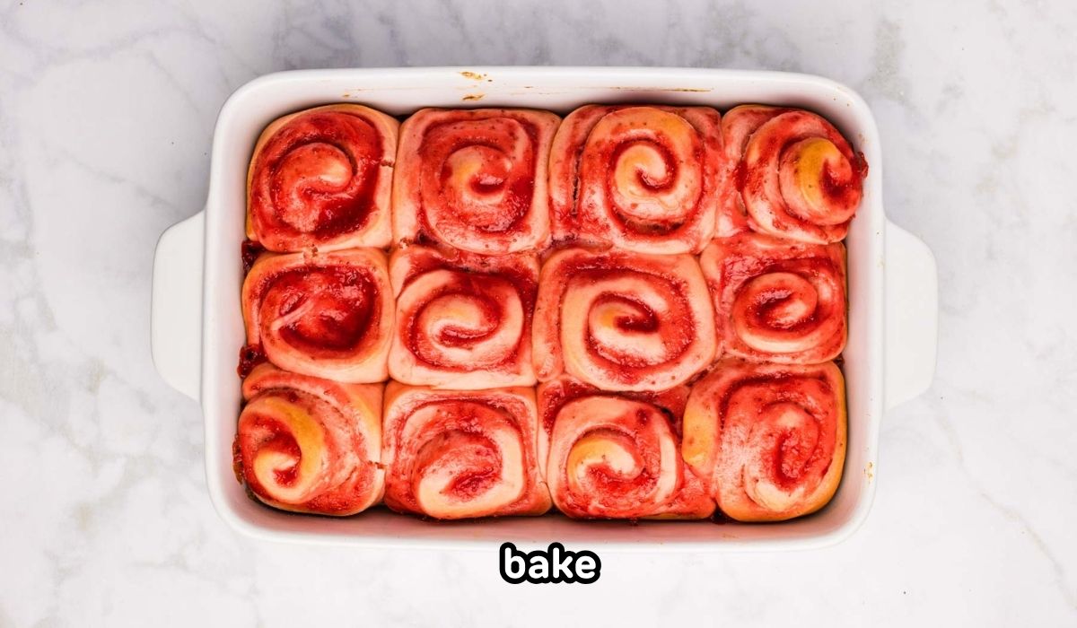 Baked strawberry cinnamon rolls in a white baking dish.
