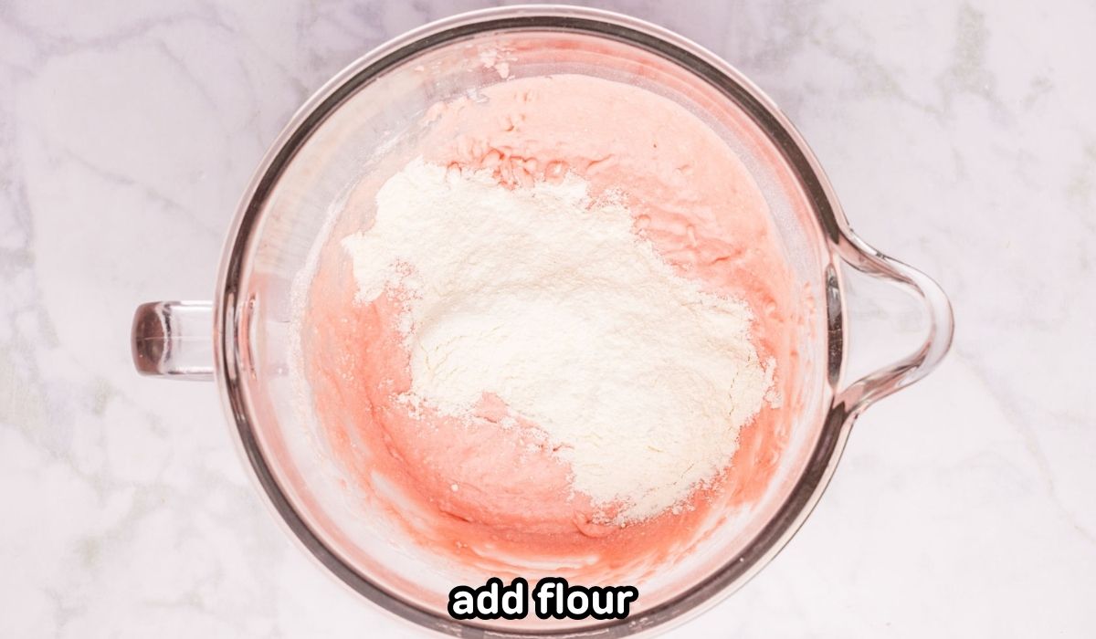 Flour added to the cake and yeast mixture in a mixing bowl.