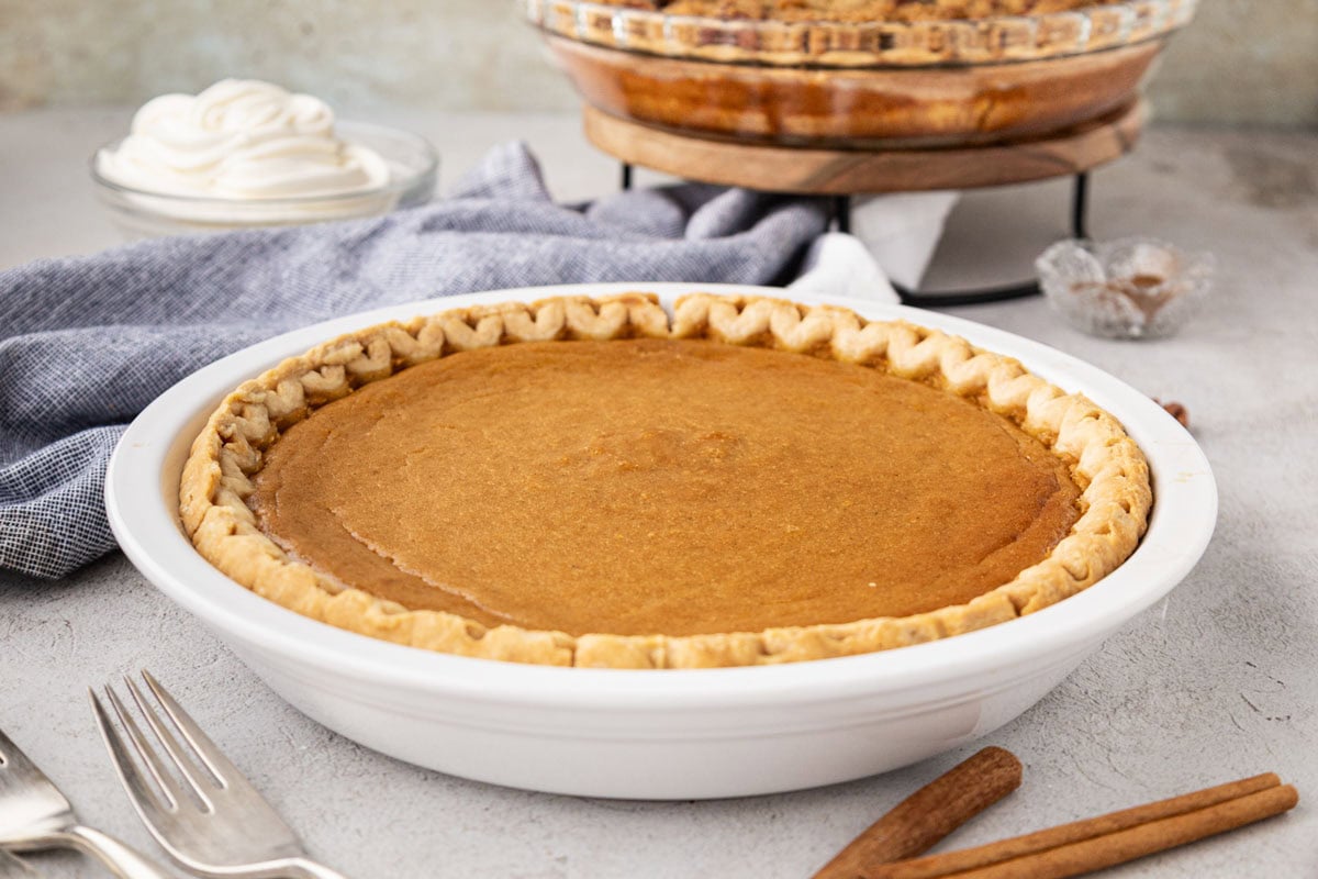 A whole southern sweet potato pie baked, and a white pie dish.