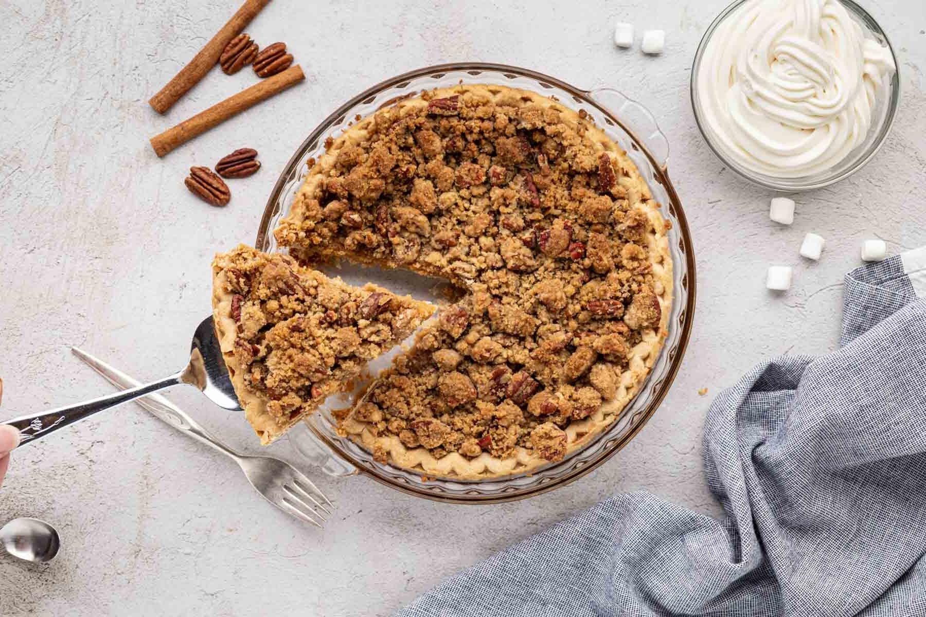 A pie server, removing a slice of sweet potato pie with pecan crumb topping.