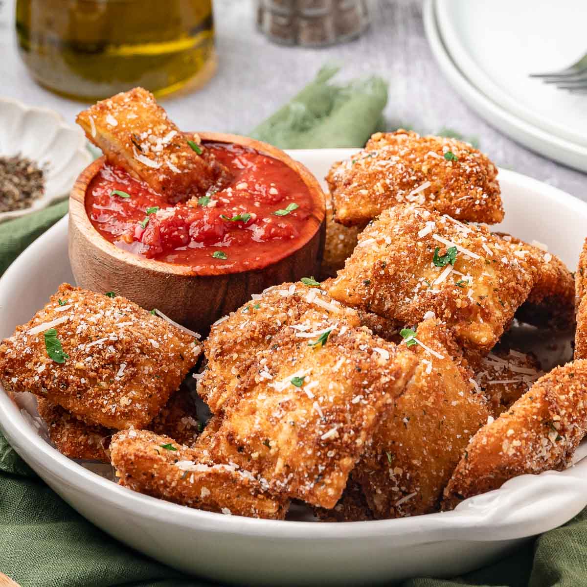Fried ravioli served in a bowl with a side of marinara sauce.