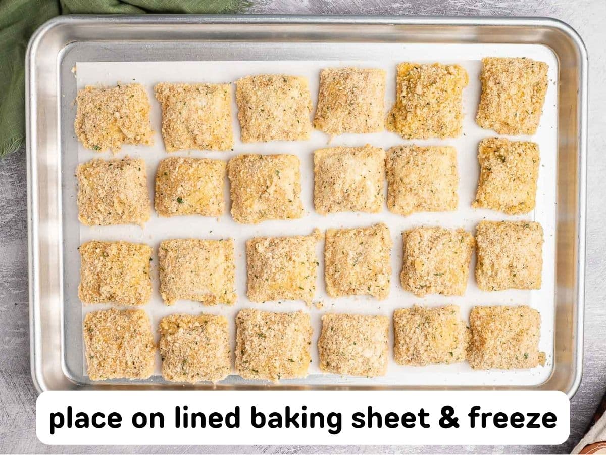 Breaded ravioli lined up on a sheet pan lined with parchment paper.
