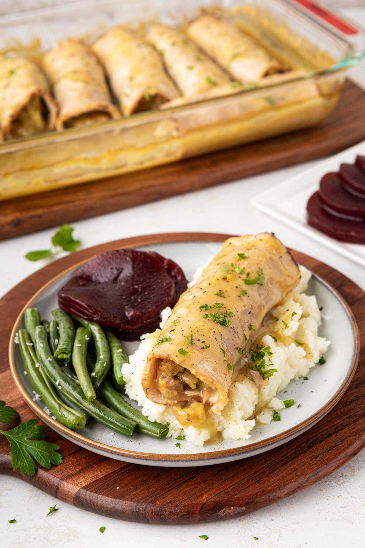 A turkey and stuffing roll up, served over mashed potatoes with green beans and cranberry sauce.
