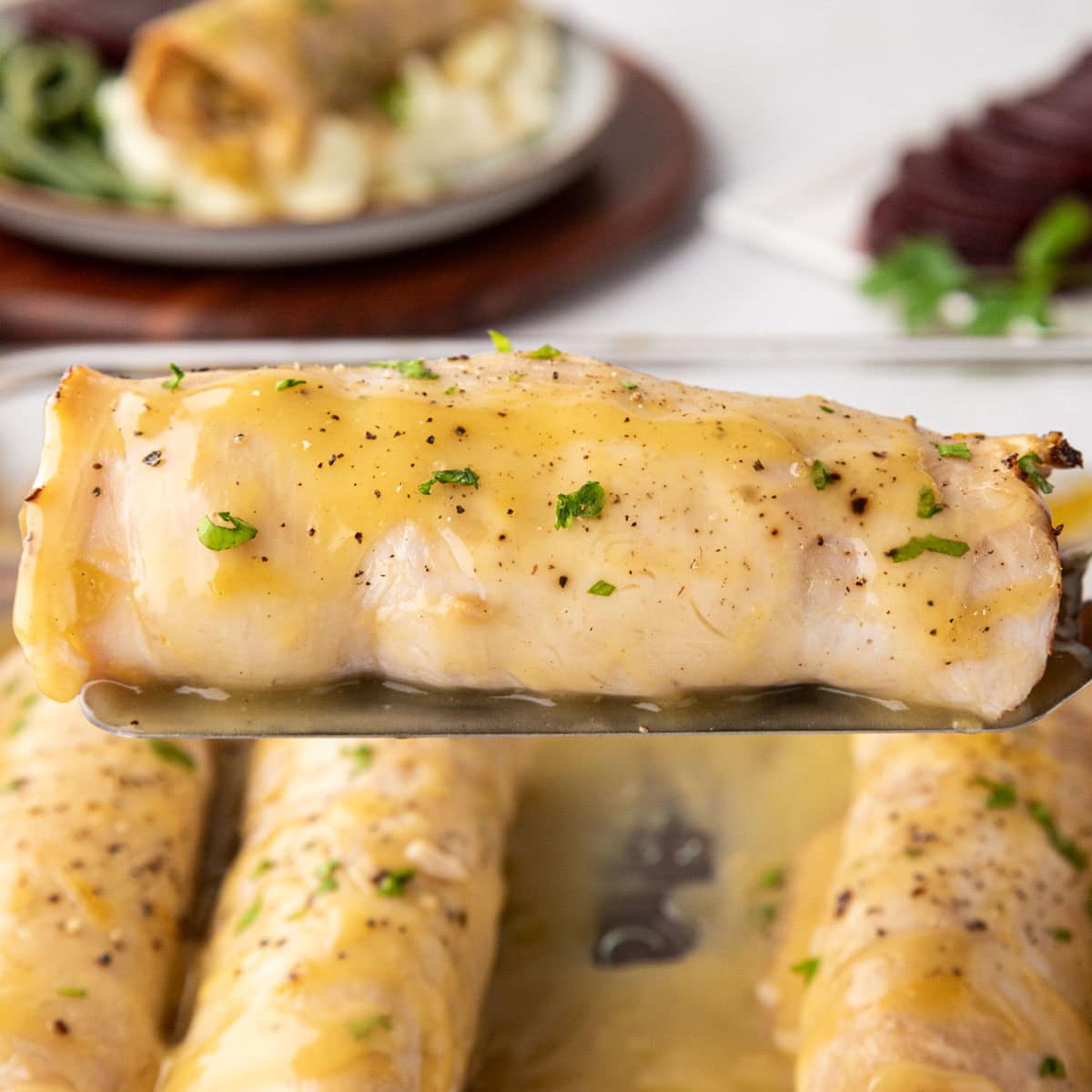Removing a turkey rollup with stuffing from the baking dish with a spatula.