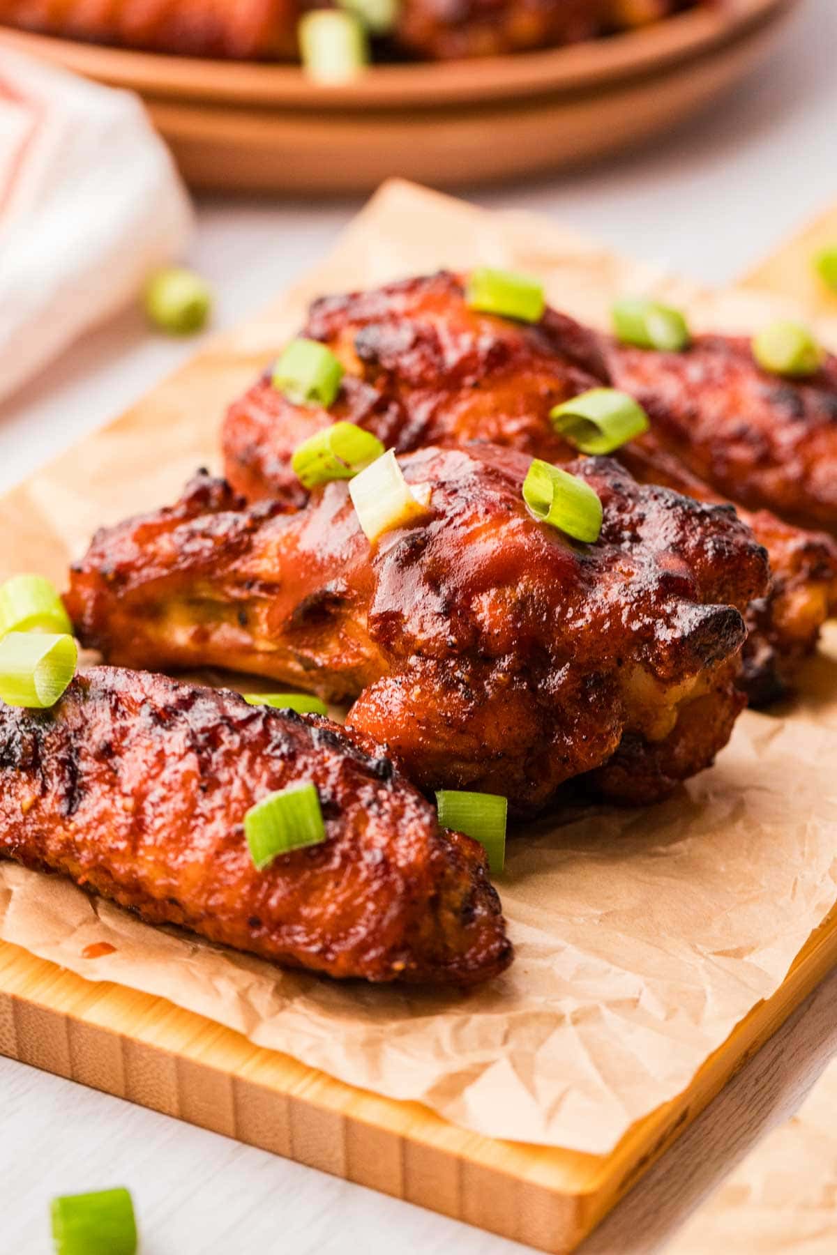 Air fryer BBQ chicken wings on a wooden board lined with parchment paper.