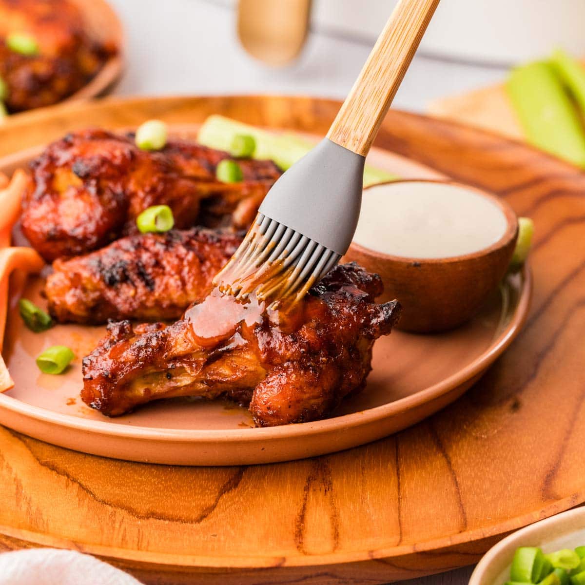 Brushing a BBQ glaze on a wing on a plate.