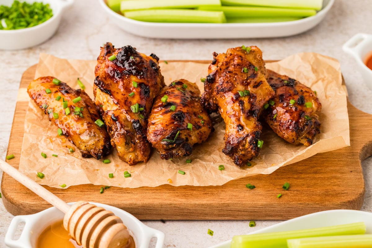 Hot honey chicken wings served on a board lined with parchment.