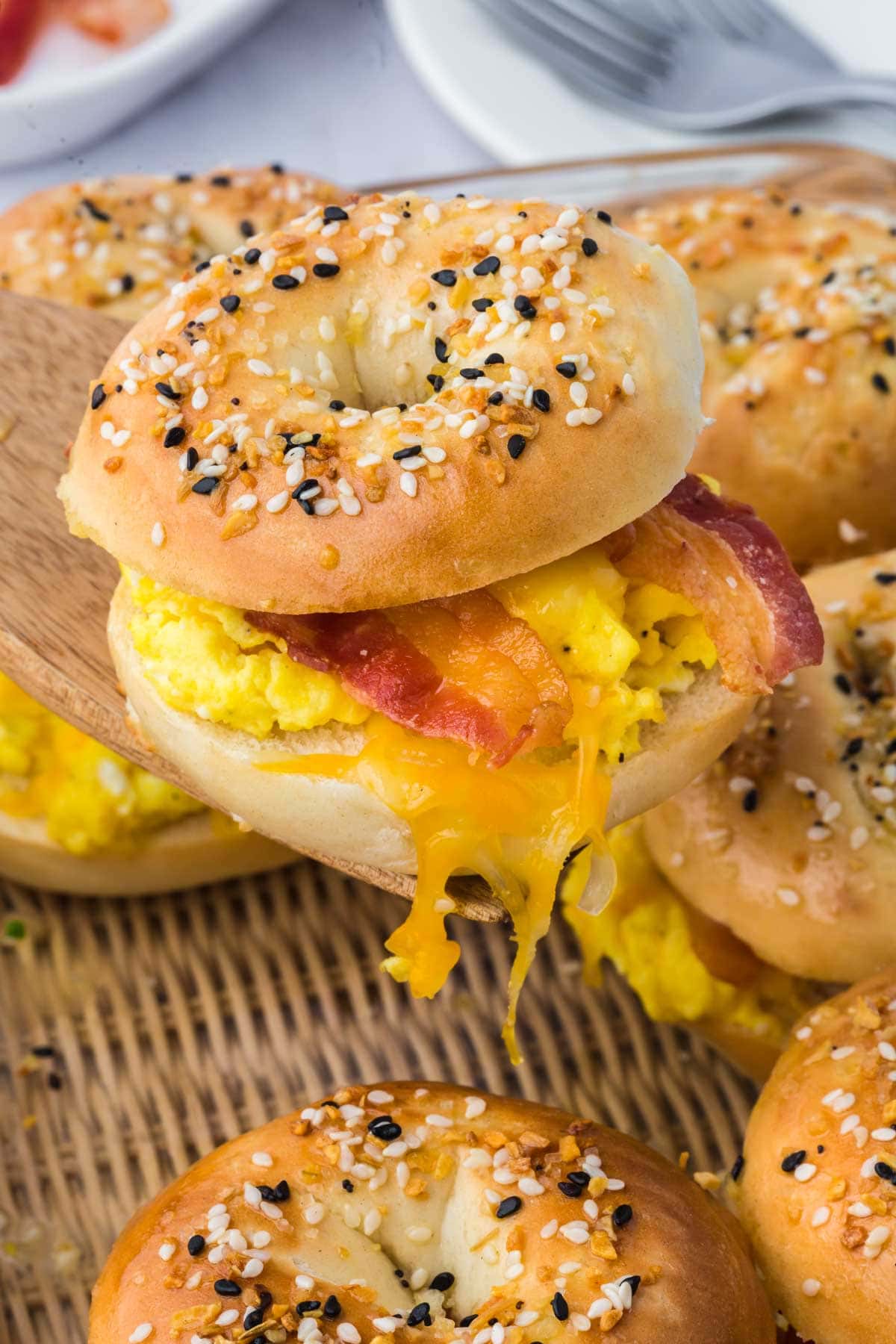 Spatula holding a breakfast bagel slider with eggs and bacon above more sliders.