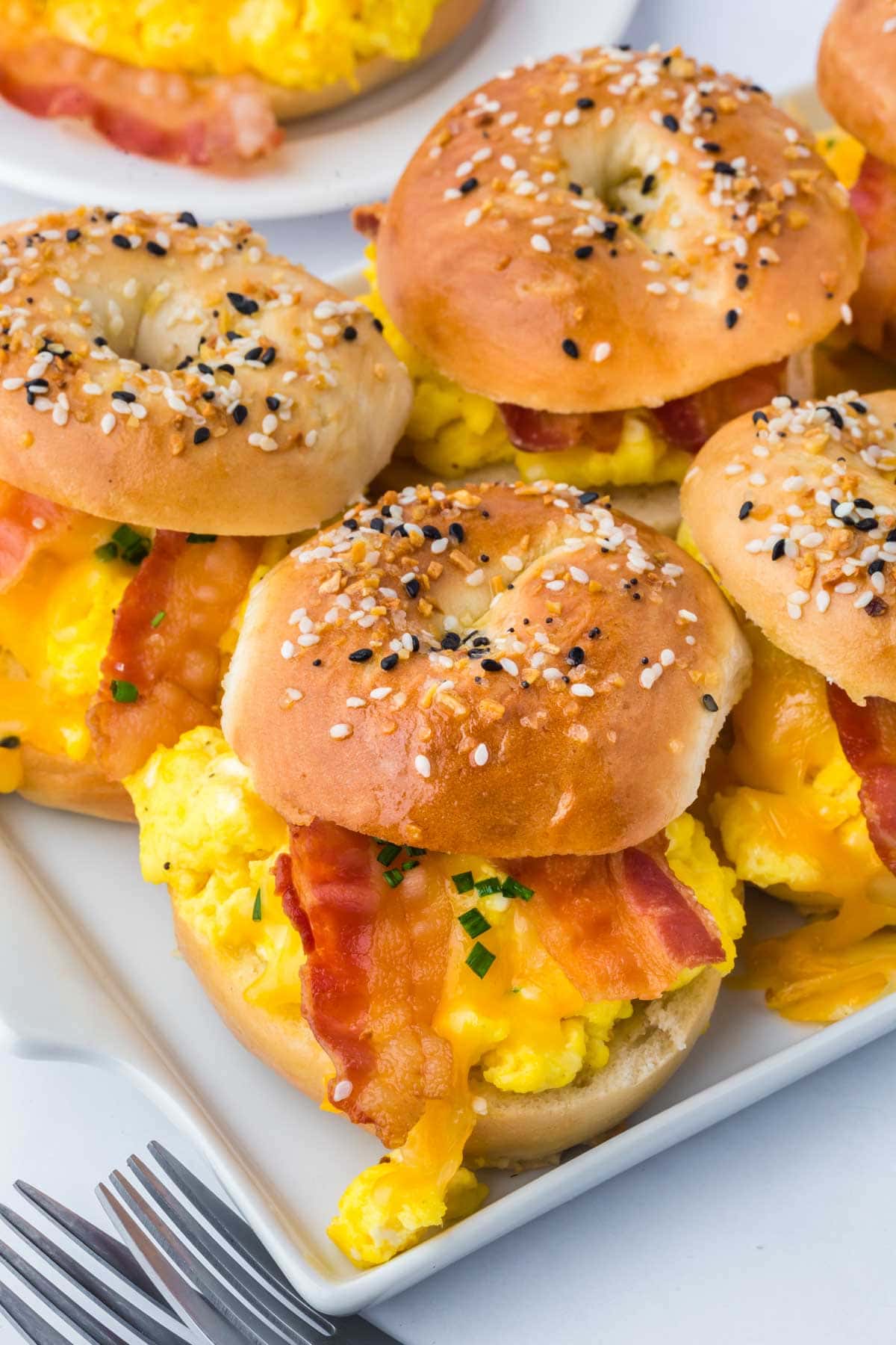 Breakfast bagel sliders with eggs and bacon on a white serving dish.