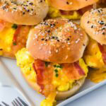 Breakfast bagel sliders with eggs and bacon in a white platter.
