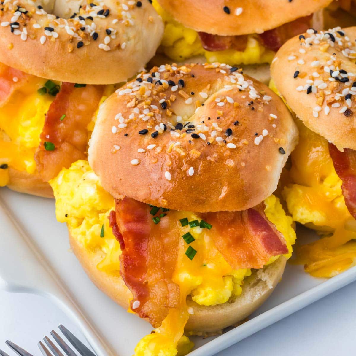 Breakfast bagel sliders with eggs and bacon in a white platter.