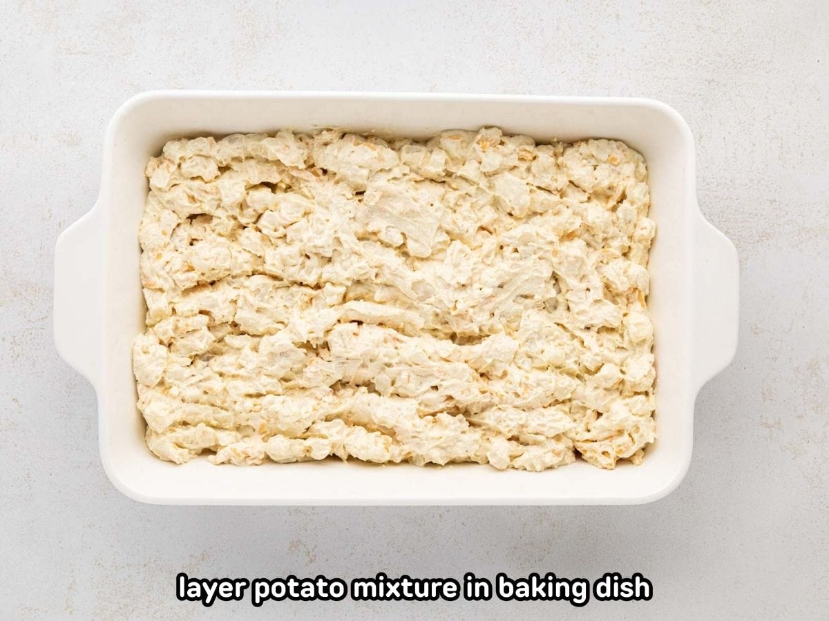 An image of layering potato mixture in the bottom of the baking dish.