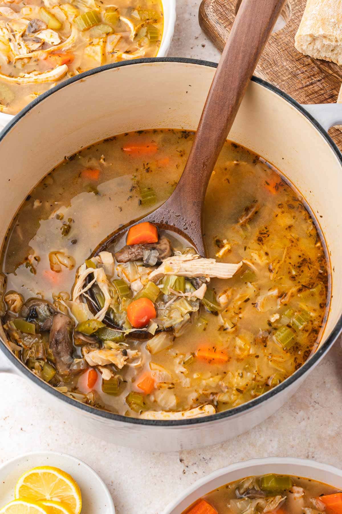 Large Dutch oven pot of chicken cabbage soup with a wooden spoon in the pot.