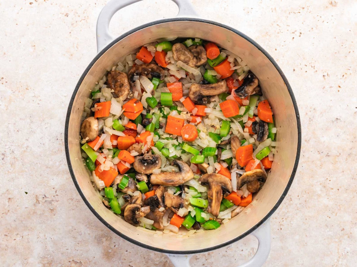 Vegetables sautéing in a large soup pot.