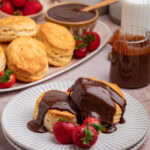 Close up of two biscuits on a plate with chocolate gravy over the top.