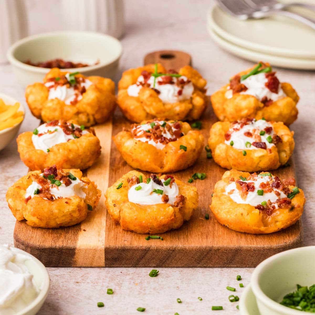Side view of loaded tater tot cups lined up on a wooden board.