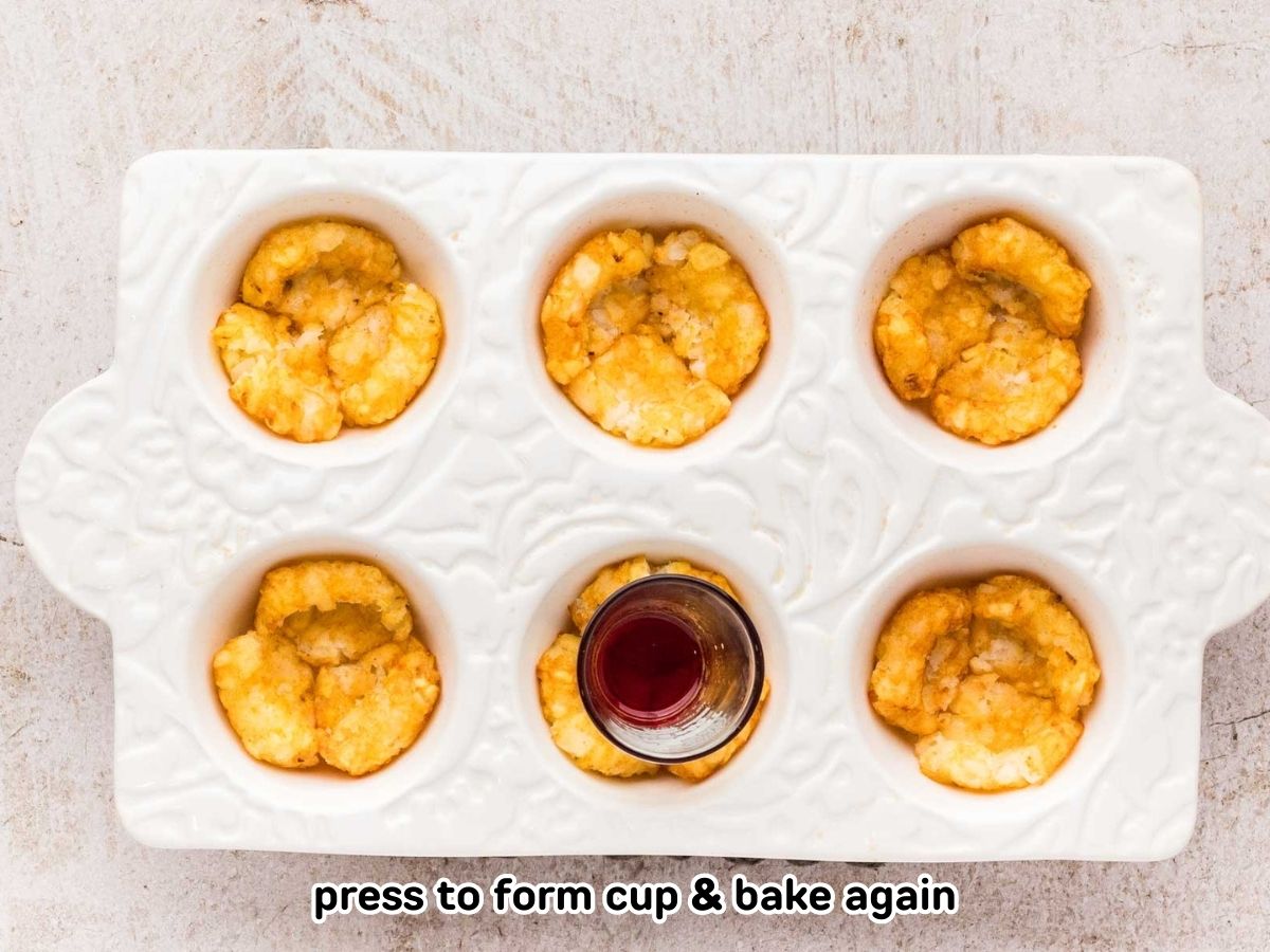 Tater tots smashed with a shot glass in a muffin dish.
