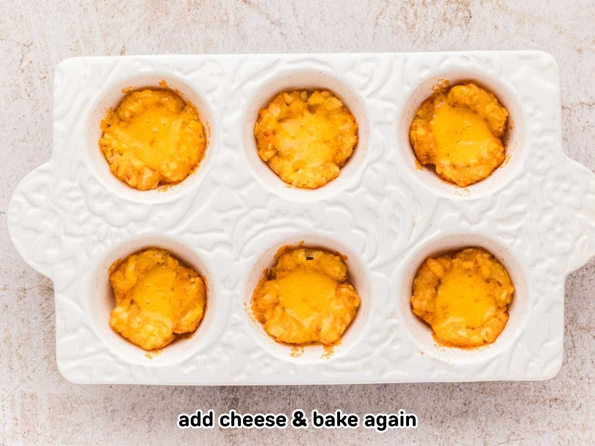 Tater tot cups in a muffin dish with melted cheese in the cups.