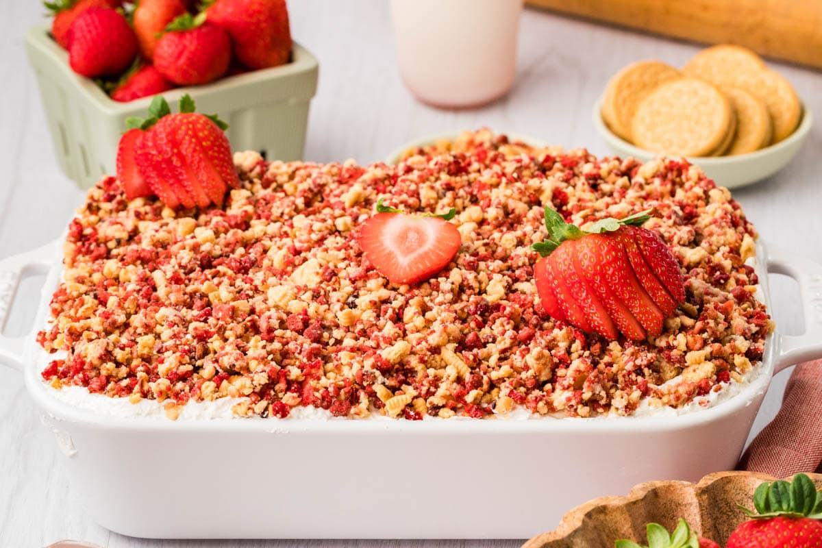 Finished strawberry crunch cake in a baking dish with fresh strawberries on top.