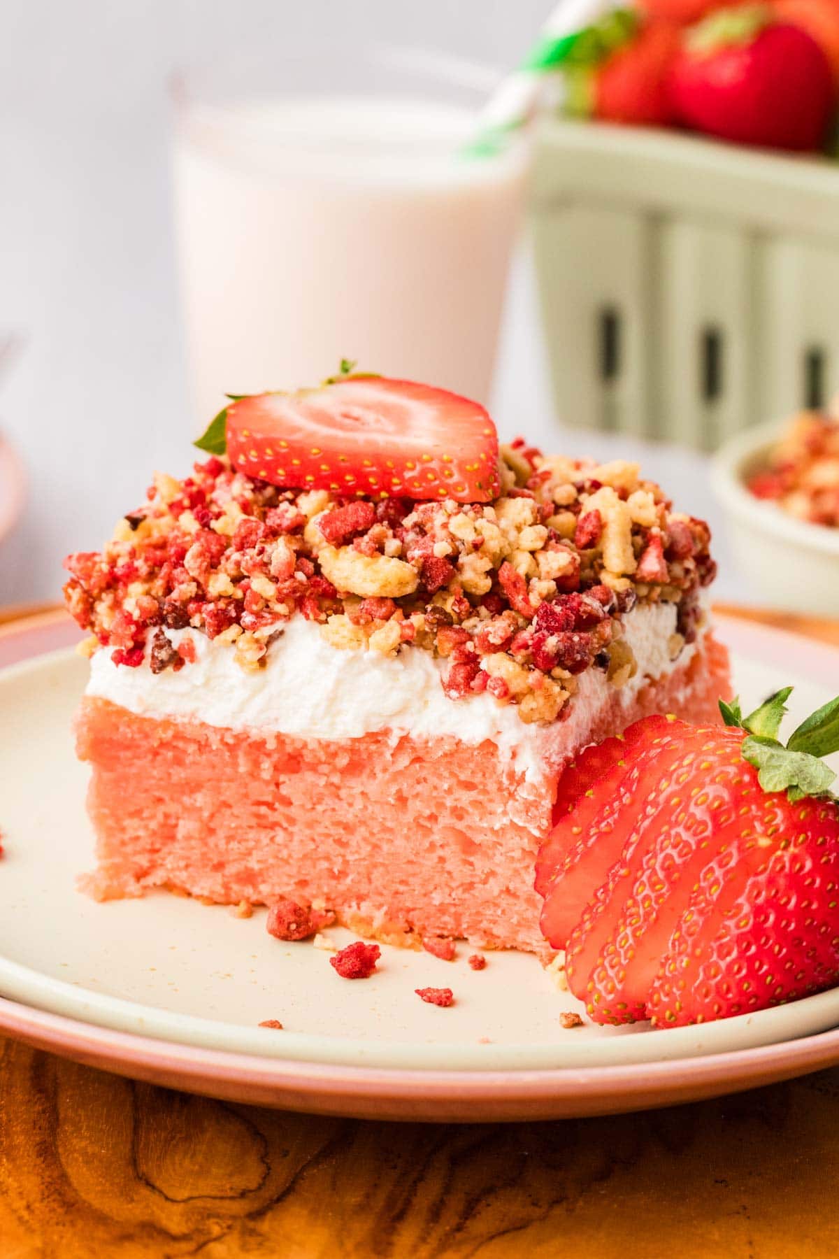 Slice of strawberry crunch cake on a plate garnished with fresh strawberries.