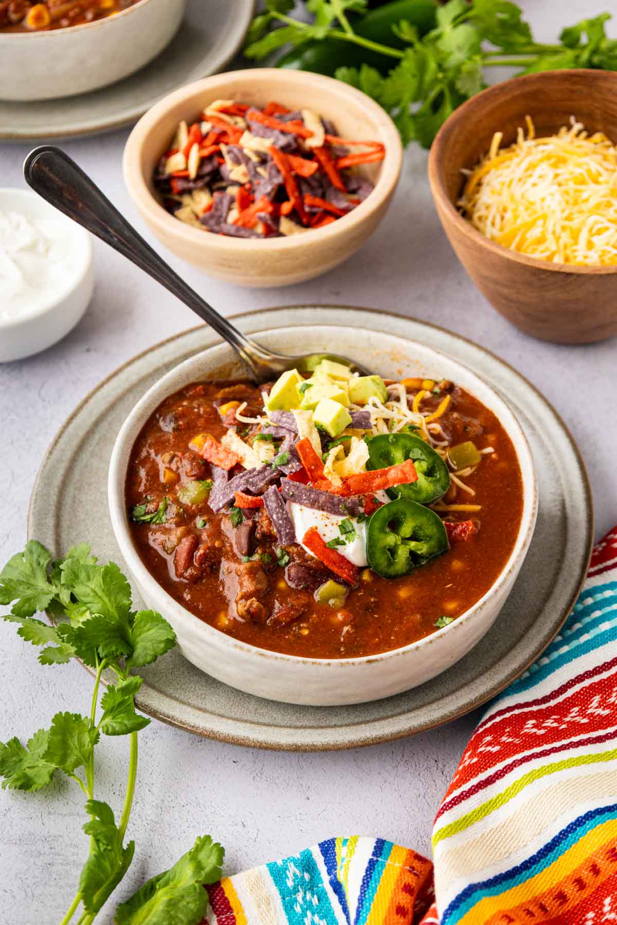 A bowl of taco soup on a tablescape with the toppings in the background.