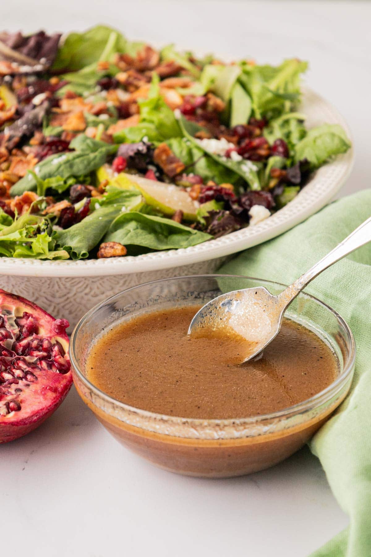 A bowl with apple vinaigrette with a salad in the background.