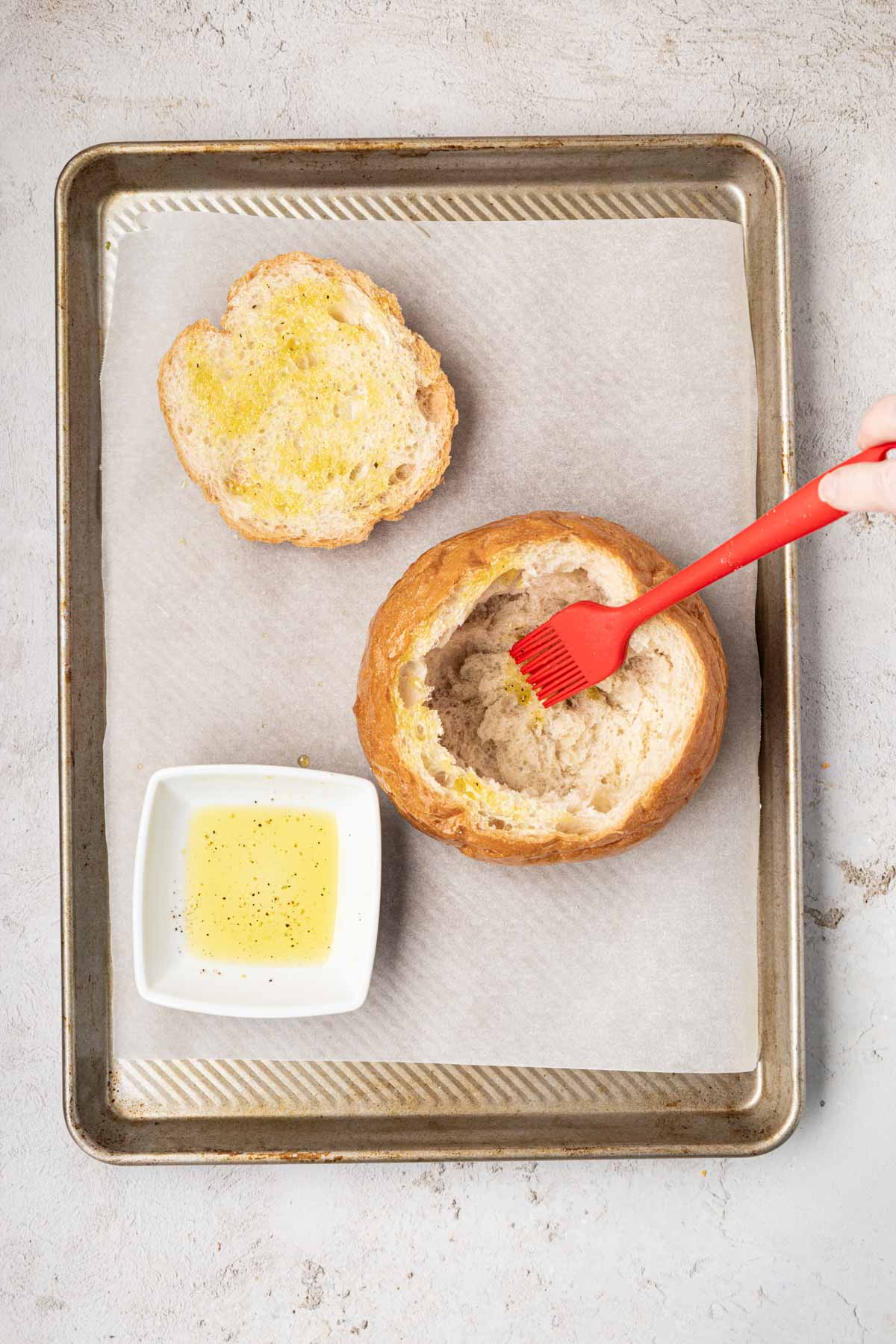 Brushing the hollowed out bread bowl with melted butter.