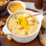 Broccoli cheddar soup in a white bowl with toasted croutons on top.