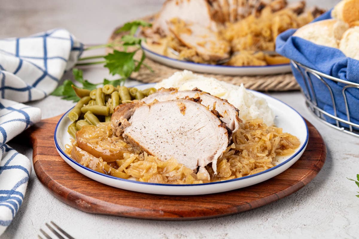 Pork Roast with sauerkraut on a white plate with green beans.