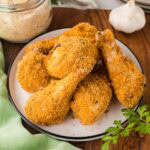 Shake and bake chicken drumsticks on a plate.