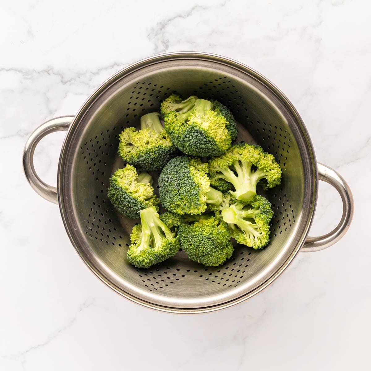 Cooked broccoli strained in a colander.