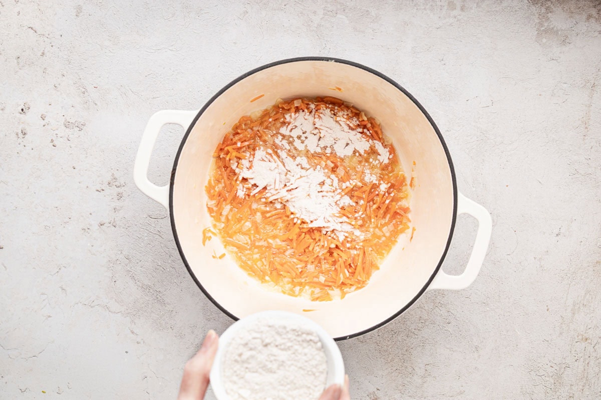 Stirring in flour to create roux with sautéed veggies.