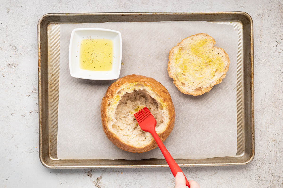 Brushing oil on top and inside of bread bowl.