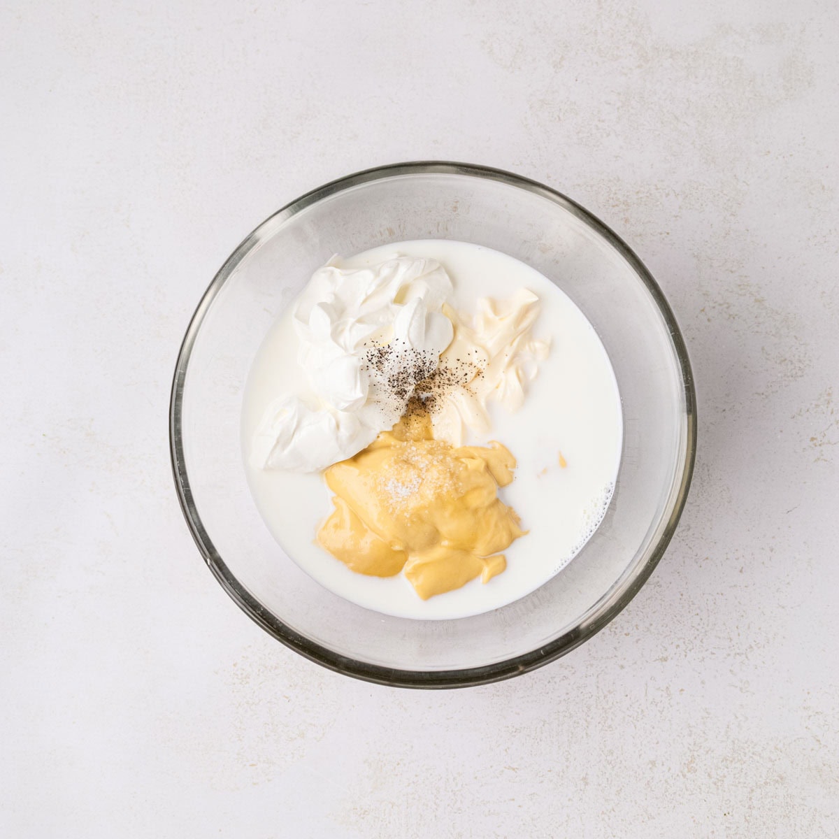 Cream of chicken soup, sour cream, mayo, and milk in a small bowl.