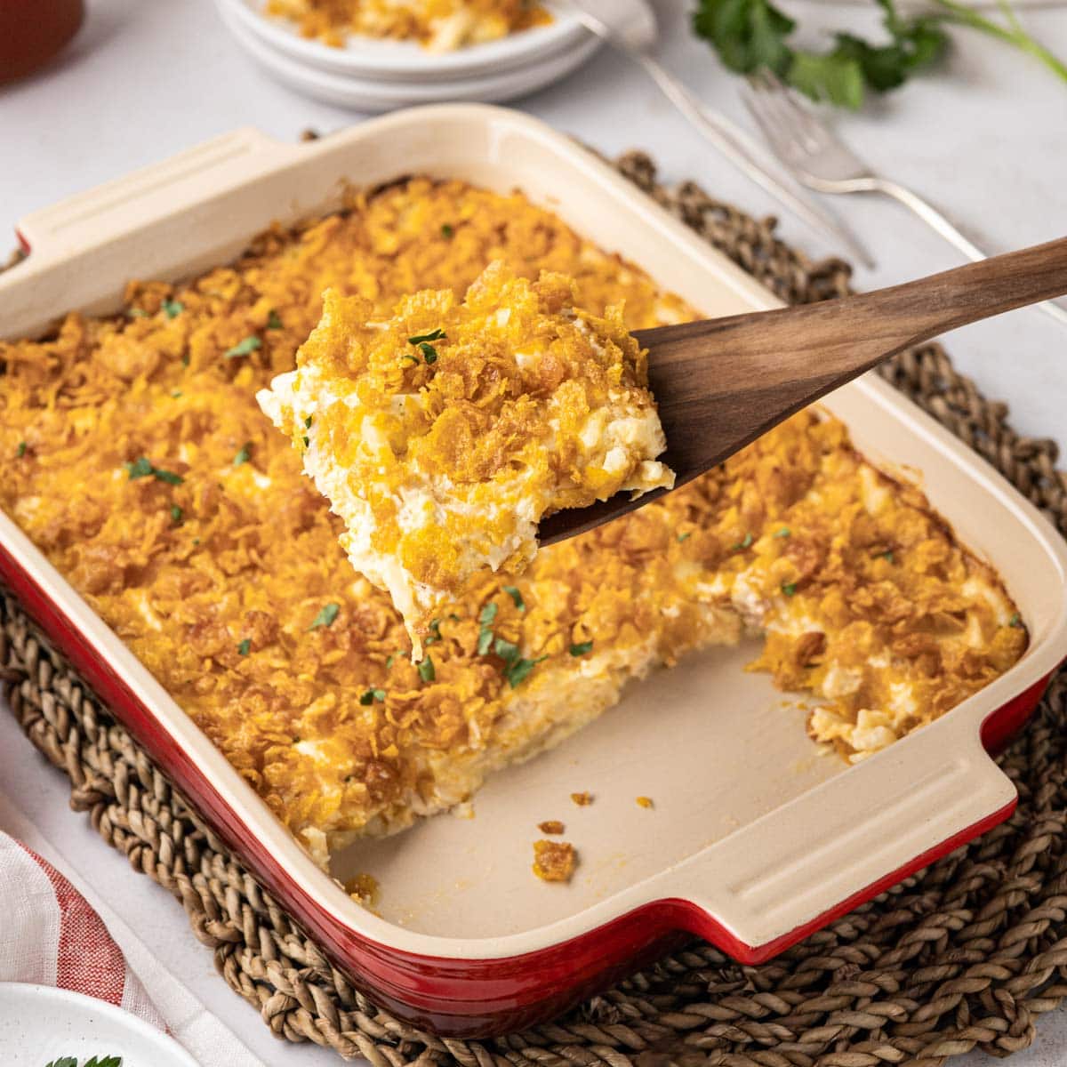 Spatula with chicken hash brown casserole on it, scooped from a baking dish.