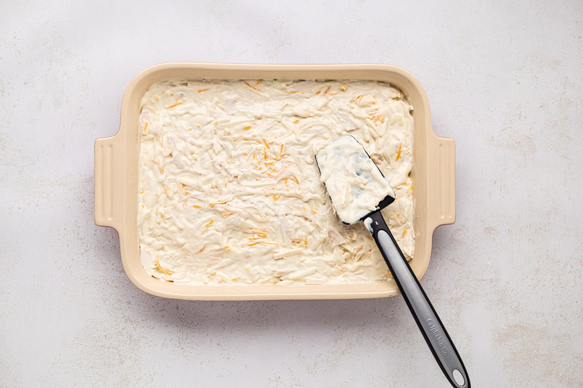Chicken hash brown casserole mixture layered into a baking dish.
