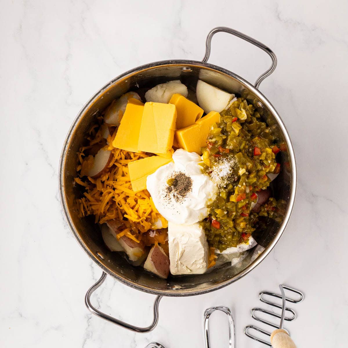 Cooked potatoes with cheese, sour cream, cream cheese, salt, pepper, diced peppers, added.