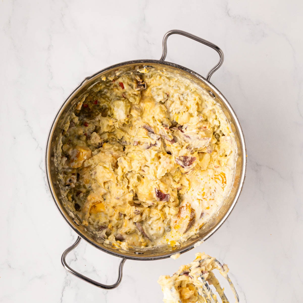 Potatoes and ingredients after being mixed with a hand mixer in a pot.