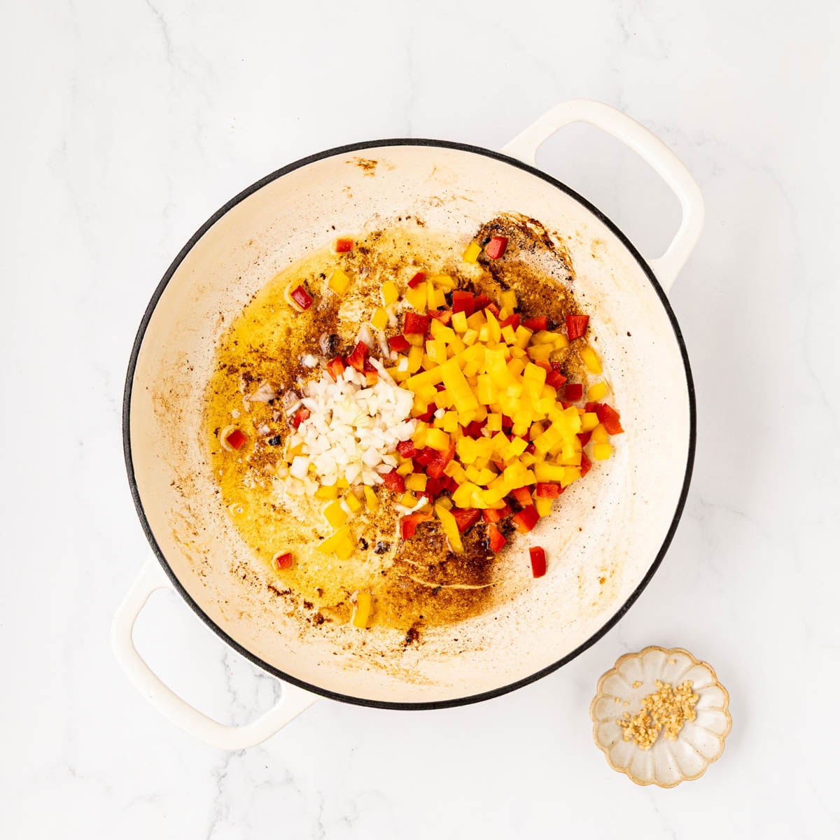 Diced onions and bell peppers in a skillet.