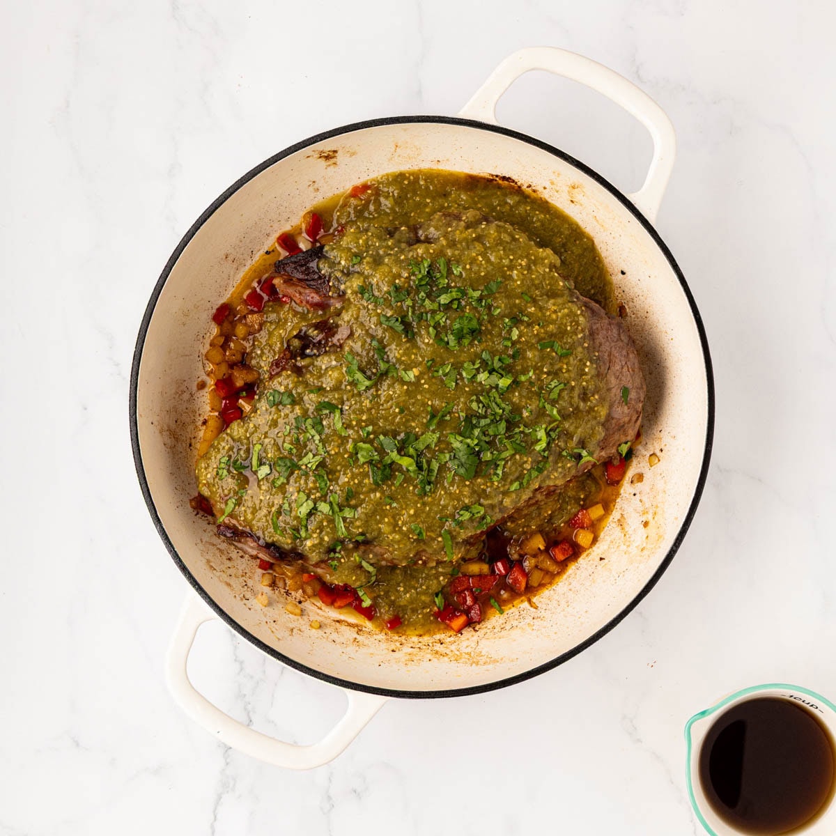 Adding salsa and cilantro to the Mexican pot roast before braising.