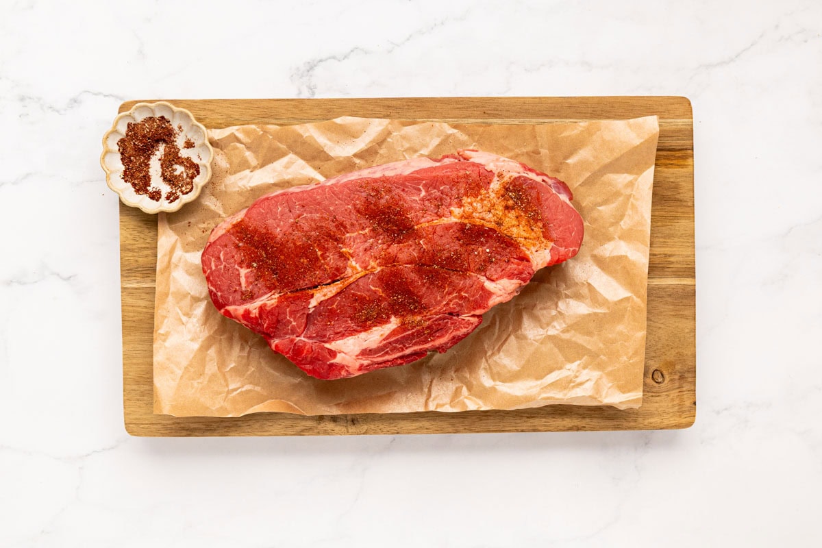 Pot roast seasoned with elote seasoning on a wooden board.