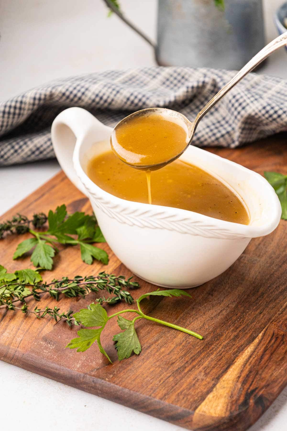 Ladle scooping up pork gravy from a white gravy boat.