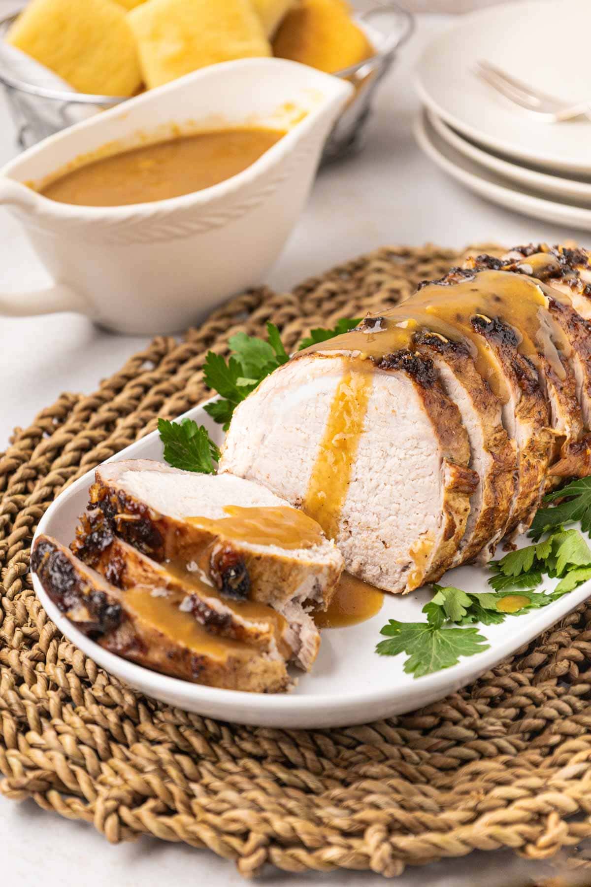 Sliced oven pork roast on a serving platter with gravy on top.