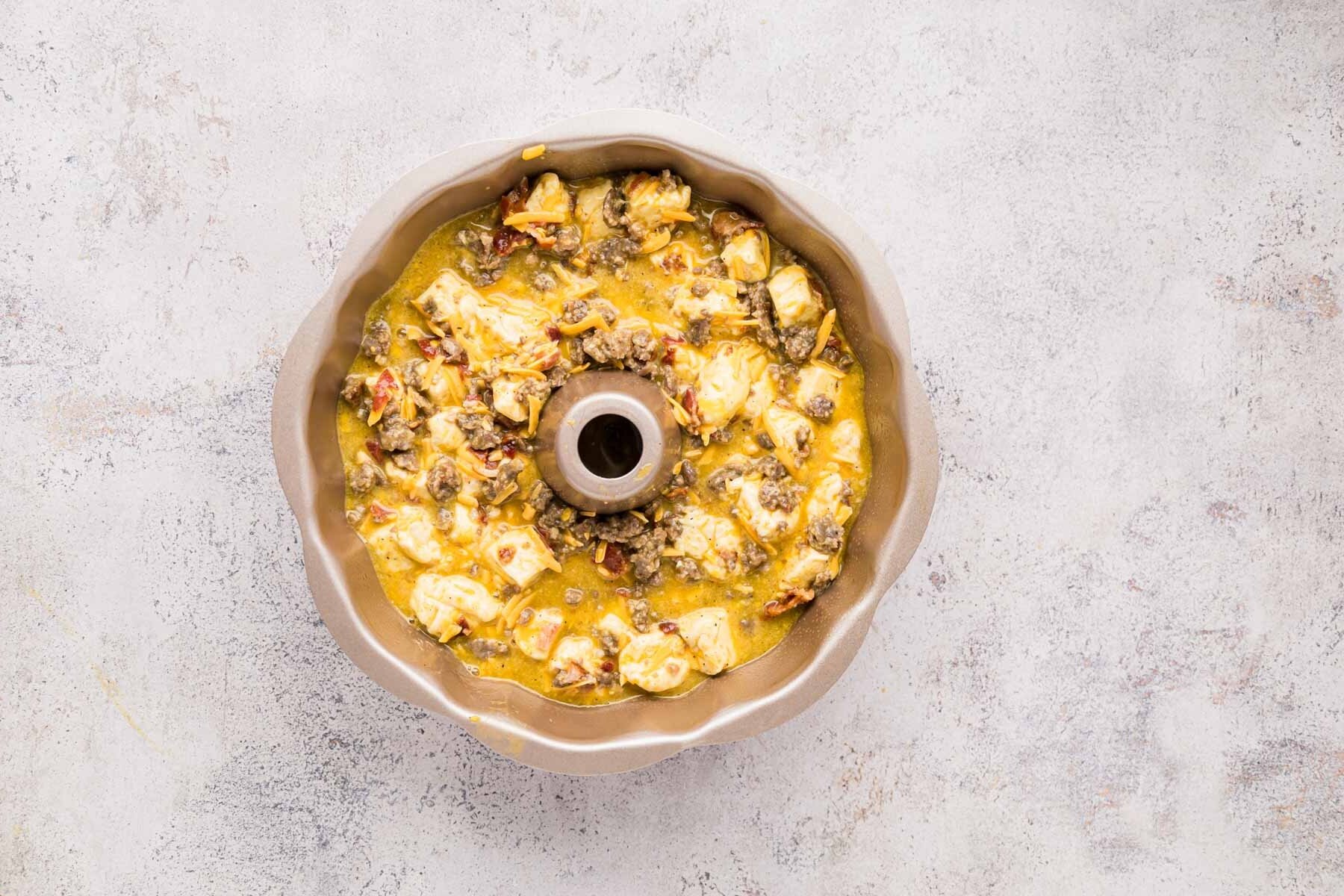Biscuit breakfast casserole mixture placed into a bundt pan.