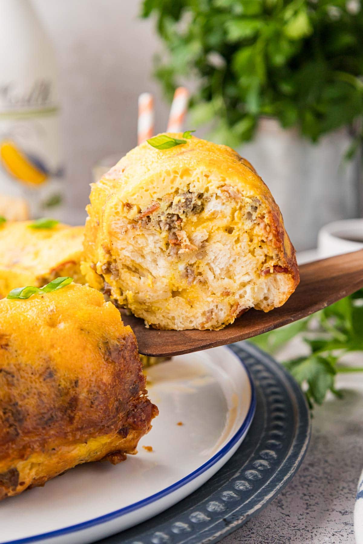 Slice of breakfast bundt casserole with biscuits being taken by a wooden spatula.