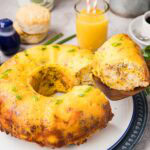 Slice of breakfast casserole with biscuits on a wooden spatula above the rest of the casserole.