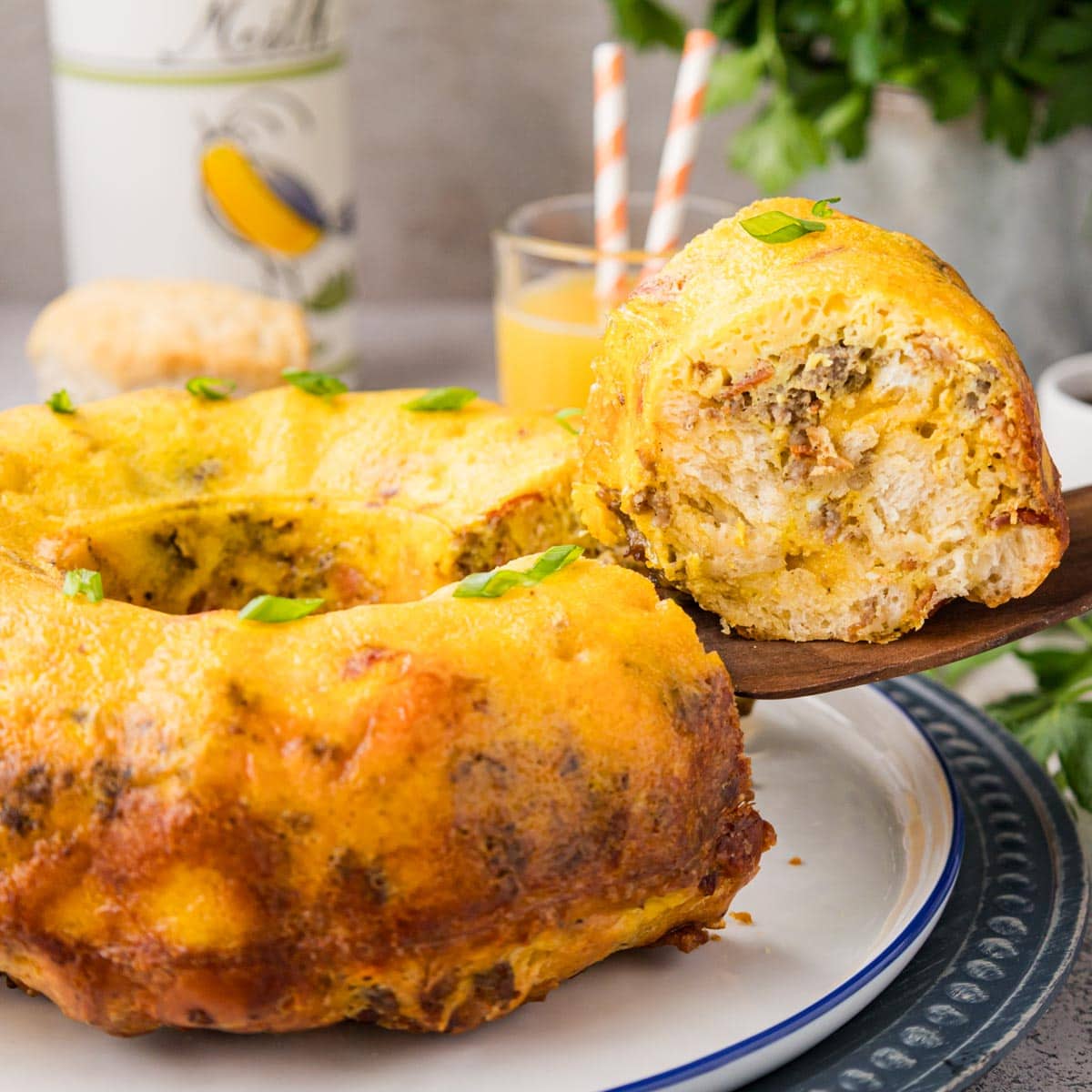 Wooden spatula taking a slice of breakfast casserole from a plate.
