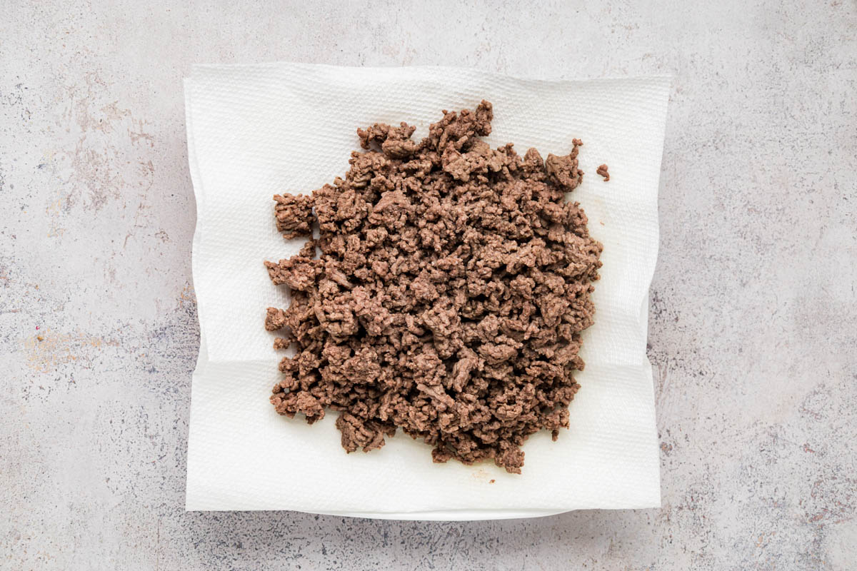 Ground beef on a plate lined with paper towels.