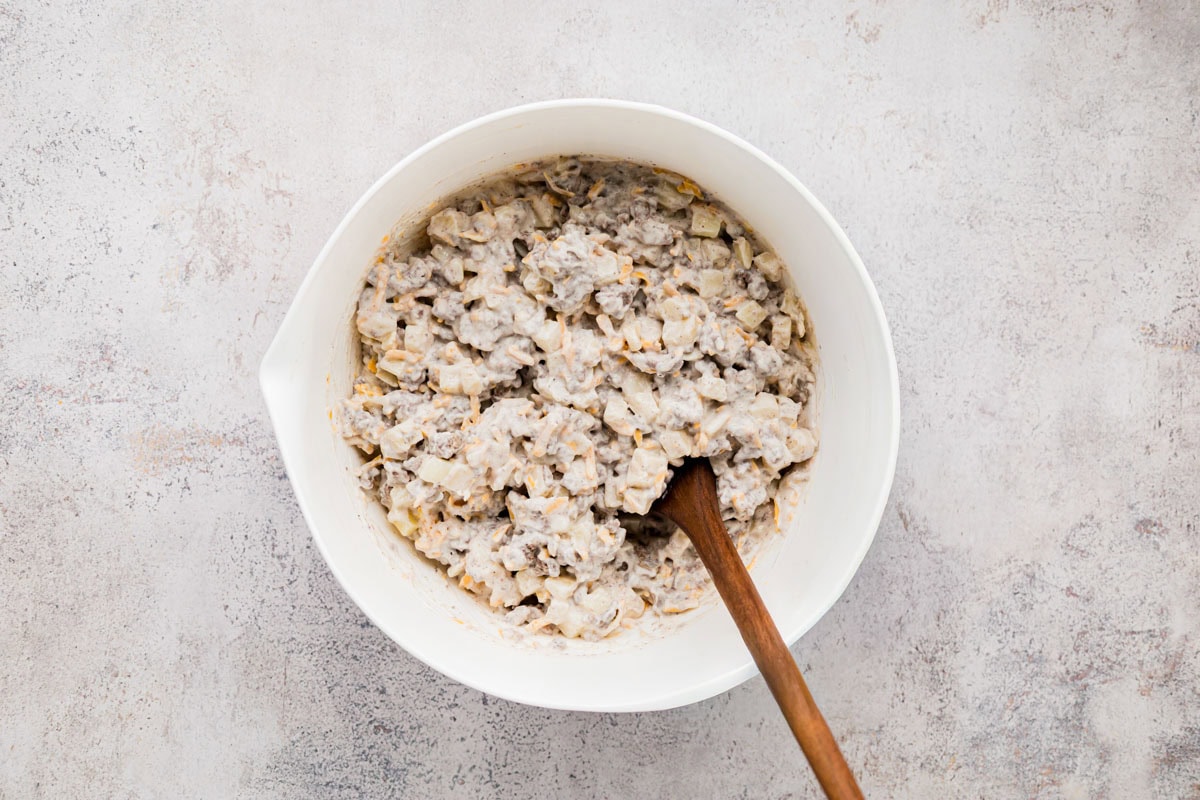 Ground beef folded with the soup mixture and cheese in a bowl.